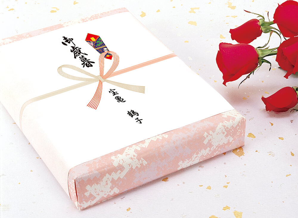 「御歳暮」の表書きと紅白の花結びの水引ののし紙を掛けた贈答品と、赤いバラ